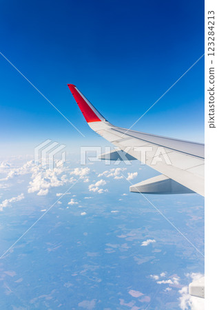 View from the airplane window at a beautiful cloudy sky and the airplane wing View from the airplane window at a beautiful cloudy sky and the airplane wing 123284213