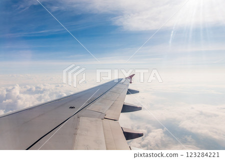 View from the airplane window at a beautiful cloudy sky and the airplane wing View from the airplane window at a beautiful cloudy sky and the airplane wing 123284221