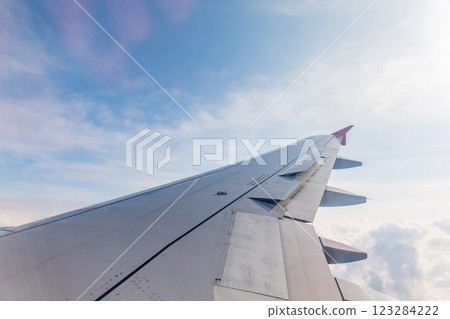 View from the airplane window at a beautiful cloudy sky and the airplane wing View from the airplane window at a beautiful cloudy sky and the airplane wing 123284222