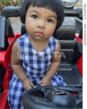 Cute Asian baby girl sitting in a red car seat. Cute Asian baby girl sitting in a red car seat. 123284560