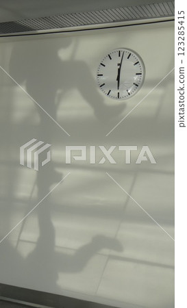 a man's shadow kicks on the wall clock 123285415