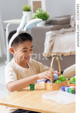 Easter fun for all. Kids with bunny ears joyfully paint Easter eggs with brushes 123285483