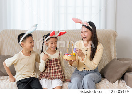 Easter family joy. A cheerful mother and kids with bunny ears celebrate Easter at home Easter family joy. A cheerful mother and kids with bunny ears celebrate Easter at home 123285489