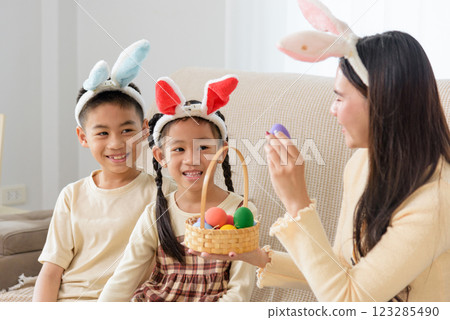 Easter family joy. A cheerful mother and kids with bunny ears celebrate Easter at home Easter family joy. A cheerful mother and kids with bunny ears celebrate Easter at home 123285490