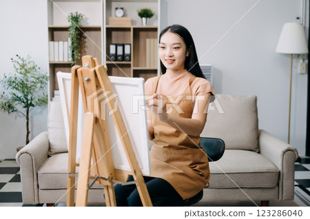 sian Female painter do artwork in art workshop, painting supplies, oil pastels, two canvas easel, creative space 123286040