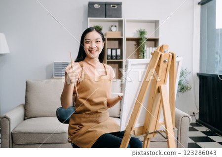 sian Female painter do artwork in art workshop, painting supplies, oil pastels, two canvas easel, creative space 123286043