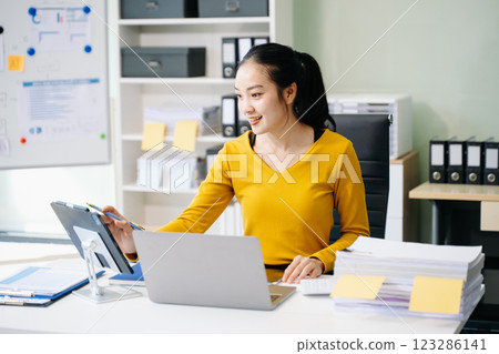 Asian Businesswoman Analyzing Finance on Tablet and Laptop at modern Office Desk tax Asian Businesswoman Analyzing Finance on Tablet and Laptop at modern Office Desk tax 123286141