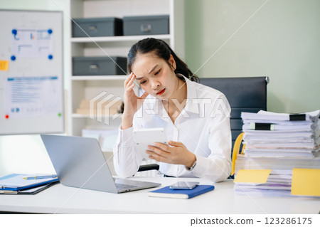 Woman who is tired and overthinking from working with tablet and laptop at modern office. Woman who is tired and overthinking from working with tablet and laptop at modern office. 123286175