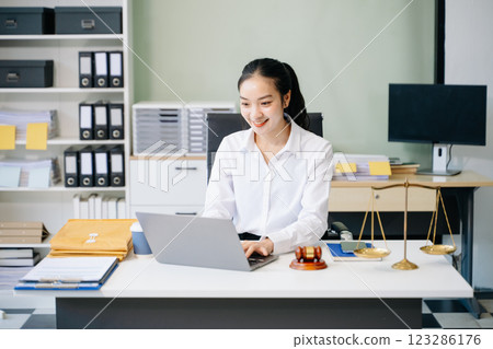 female lawyer celebrating success with documents at a desk, featuring a gavel, scales of justice, 123286176