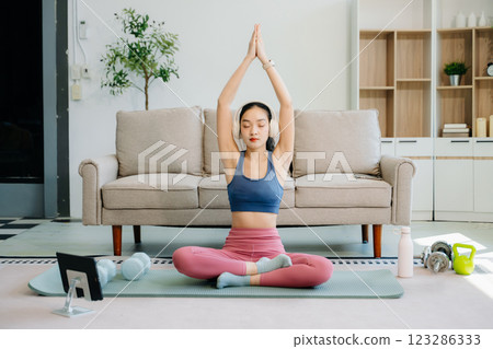 Asian Woman Doing Yoga and Watching Online Tutorials on tablet, Training Asian Woman Doing Yoga and Watching Online Tutorials on tablet, Training 123286333