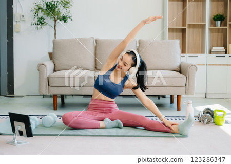 Asian Woman Doing Yoga and Watching Online Tutorials on tablet, Training 123286347