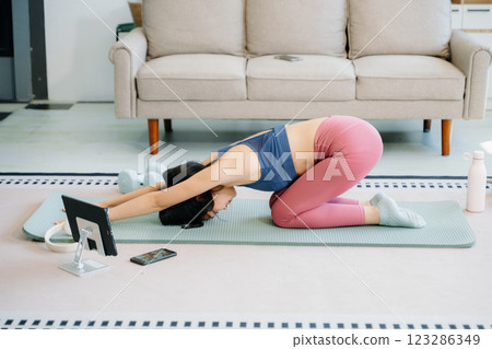 Asian Woman Doing Yoga and Watching Online Tutorials on tablet, Training 123286349