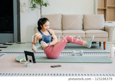 A young woman practices yoga and stretching with a mat and gym props, showcasing wellness, motivation, A young woman practices yoga and stretching with a mat and gym props, showcasing wellness, motivation, 123286379