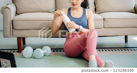 A young woman practices yoga and stretching with a mat and gym props, showcasing wellness, motivation, 123286380