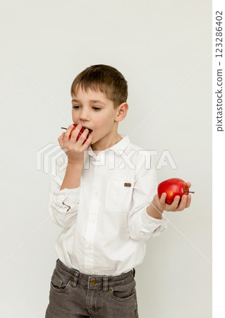A boy eats apples on an abel background. Portrait of a Boy with Apples 123286402