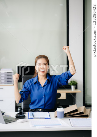 Asian female office worker business suits smiling at camera in office Asian female office worker business suits smiling at camera in office 123286428