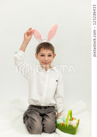 Little Boy with Easter Bunny Ears Painting Easter Eggs on White Background Little Boy with Easter Bunny Ears Painting Easter Eggs on White Background 123286433