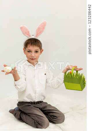 Little Boy with Easter Bunny Ears Painting Easter Eggs on White Background 123286442