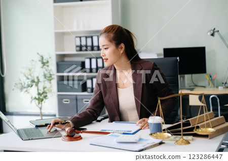Confident lawyer working on legal analysis at a modern office desk, featuring scales of justice, a gavel Confident lawyer working on legal analysis at a modern office desk, featuring scales of justice, a gavel 123286447