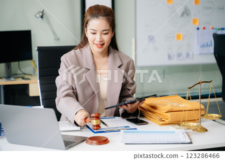 Confident lawyer working on legal analysis at a modern office desk, featuring scales of justice, a gavel 123286466