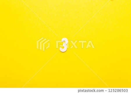 Top view of wooden number 3 three on yellow bright background. Top view of wooden number 3 three on yellow bright background. 123286503