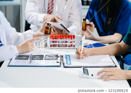 Medical team having a meeting with doctors in white lab coats and surgical scrubs seated Medical team having a meeting with doctors in white lab coats and surgical scrubs seated 123286628