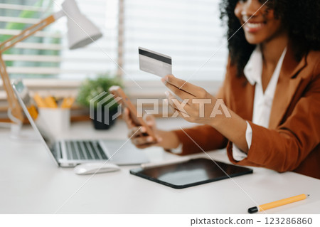 Woman using smart phone for mobile payments online shopping, omni channel, sitting on table Woman using smart phone for mobile payments online shopping, omni channel, sitting on table 123286860