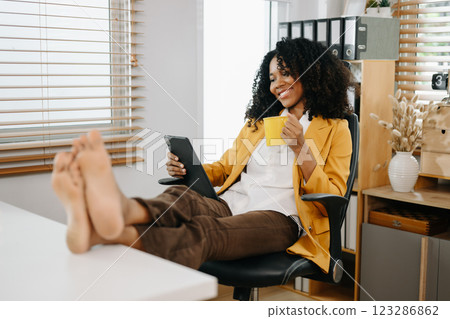 Businesswoman enjoying a coffee break in a modern office, using a tablet, relaxing Businesswoman enjoying a coffee break in a modern office, using a tablet, relaxing 123286862