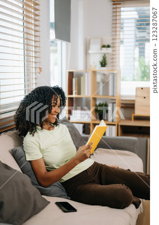 frican woman using the smartphone and tablet on the sofa at home frican woman using the smartphone and tablet on the sofa at home 123287067
