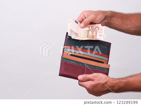 men's hands put euro banknotes in the wallet. close-up on a white background 123289199