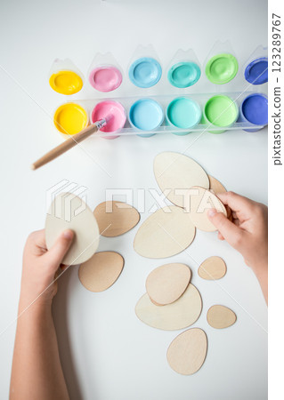 Child painting wooden eggs with pastel colors for Easter craft activity Child painting wooden eggs with pastel colors for Easter craft activity 123289767