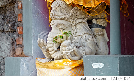 An old stone statue of Ganesha covered with moss, standing on the street An old stone statue of Ganesha covered with moss, standing on the street 123291095