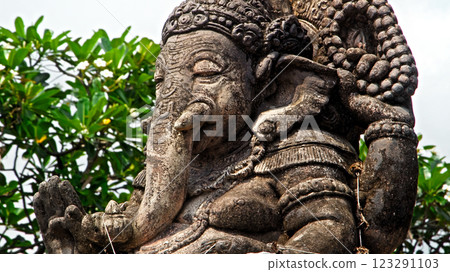 An old stone statue of Ganesha covered with moss, standing on the street An old stone statue of Ganesha covered with moss, standing on the street 123291103