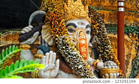 An old stone statue of Ganesha covered with moss, standing on the street An old stone statue of Ganesha covered with moss, standing on the street 123291104