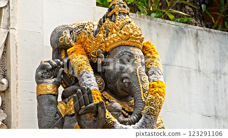 An old stone statue of Ganesha covered with moss, standing on the street An old stone statue of Ganesha covered with moss, standing on the street 123291106