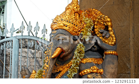 An old stone statue of Ganesha covered with moss, standing on the street An old stone statue of Ganesha covered with moss, standing on the street 123291113