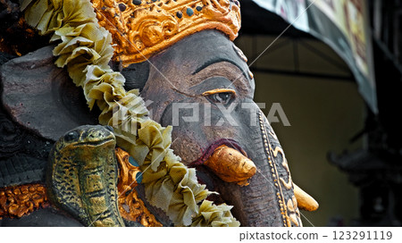 An old stone statue of Ganesha covered with moss, standing on the street An old stone statue of Ganesha covered with moss, standing on the street 123291119