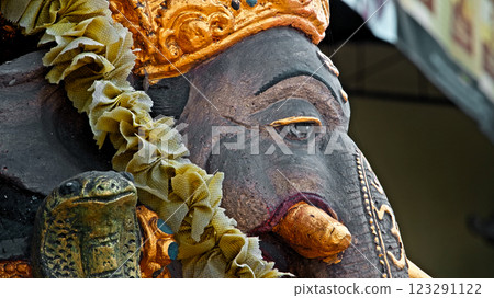An old stone statue of Ganesha covered with moss, standing on the street An old stone statue of Ganesha covered with moss, standing on the street 123291122