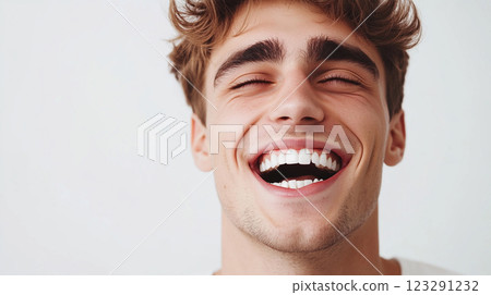 Joyful man laughing with eyes closed, radiant smile, and curly hair, radiating pure happiness and carefree spirit against a plain background. 123291232