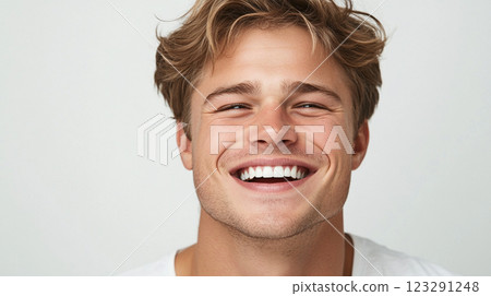 Blonde man with charming smile showcasing dental health & radiating optimism in close-up studio shot against a bright background. Blonde man with charming smile showcasing dental health & radiating optimism in close-up studio shot against a bright background. 123291248