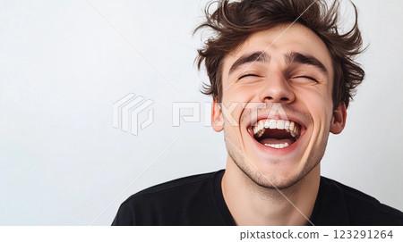 Man expressing genuine laughter. Overjoyed with eyes closed. Smiling with messy brown hair. Radiating cheerful energy. Pure bliss captured. 123291264