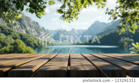 Scenic mountain vista featuring a serene lake and a rustic wooden deck, framed by lush foliage. Ideal for nature and outdoor lifestyle themes. 123291311
