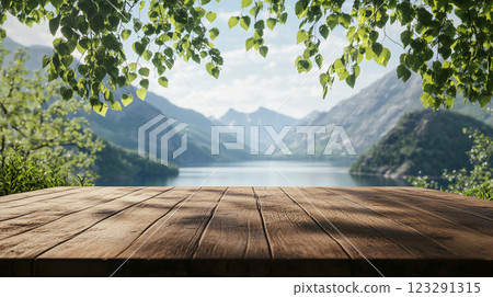 Serene lake view from wooden platform, framed by lush green leaves, offering a tranquil and inviting natural setting. Serene lake view from wooden platform, framed by lush green leaves, offering a tranquil and inviting natural setting. 123291315