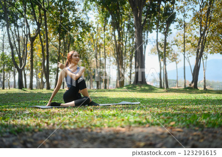 Young woman practicing yoga practicing yoga in nature, sitting in Half lord of the fishes pose 123291615