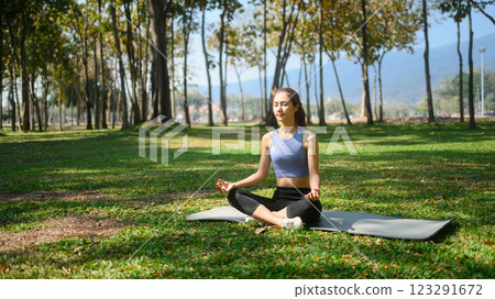 Peaceful young woman practicing meditation in a park on sunny day 123291672