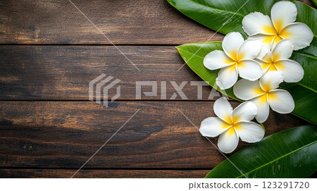 Tranquil wooden backdrop adorned with delicate frangipani blossoms, evoking serene natural beauty and timeless elegance. 123291720