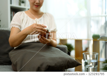 Middle aged woman holding a bottle of supplements or medication. Health consciousness and wellness concept 123291795