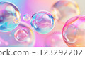 Iridescent spheres float in a colorful gradient background, creating a sense of weightlessness and visual harmony with soft reflections. 123292202