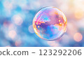A mesmerizing iridescent sphere floats against a soft, bokeh-filled backdrop of pastel hues, creating a dreamlike, ethereal atmosphere. 123292206
