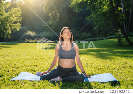 Young pregnant woman meditating in the park in the morning Young pregnant woman meditating in the park in the morning 123292241